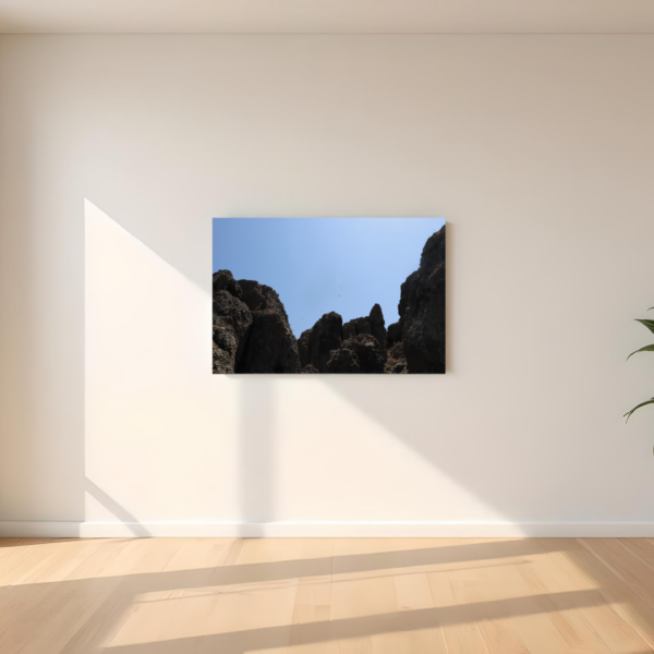 Obraz na płótnie przedstawiający skalne klify pod czystym niebem zawieszony w jasnym, minimalistycznym wnętrzu.
